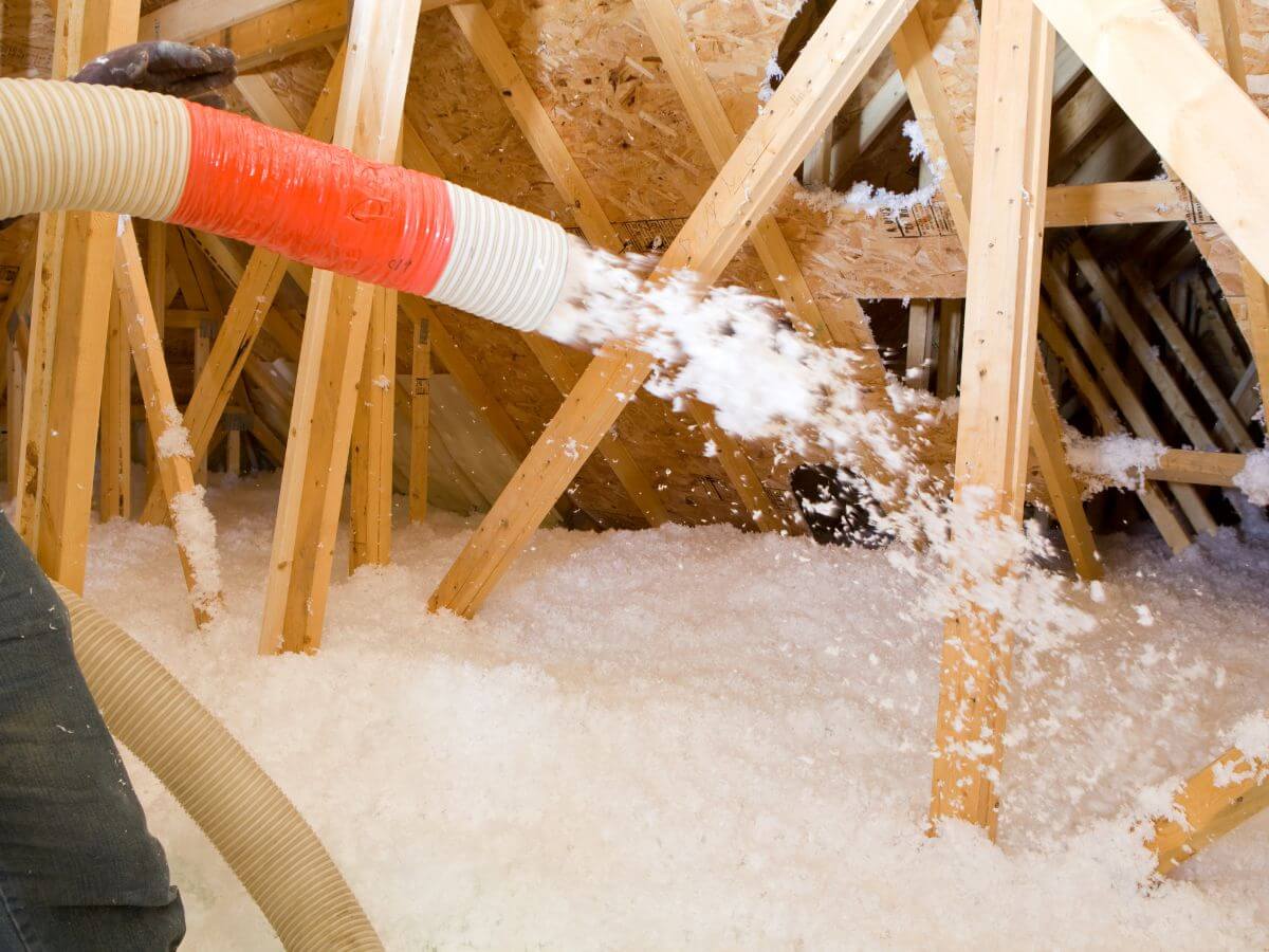 Worker spraying blown fiberglass attic insulation dallas tx